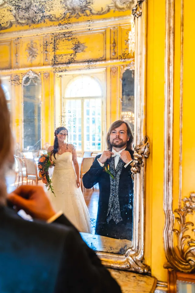 Brautpaar spiegelt sich in einem goldenen Spiegel im Festsaal