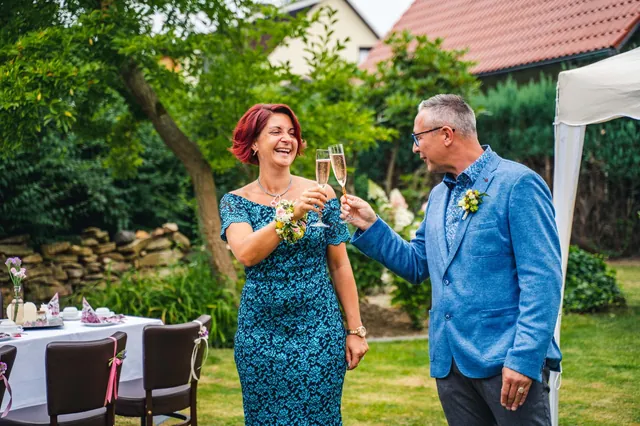 Zwei Hochzeitsgäste stoßen im Garten mit Sekt an