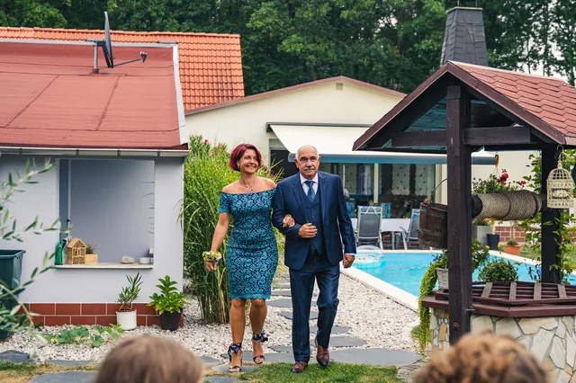 Hochzeitsgäste gehen durch einen Garten mit Pavillon