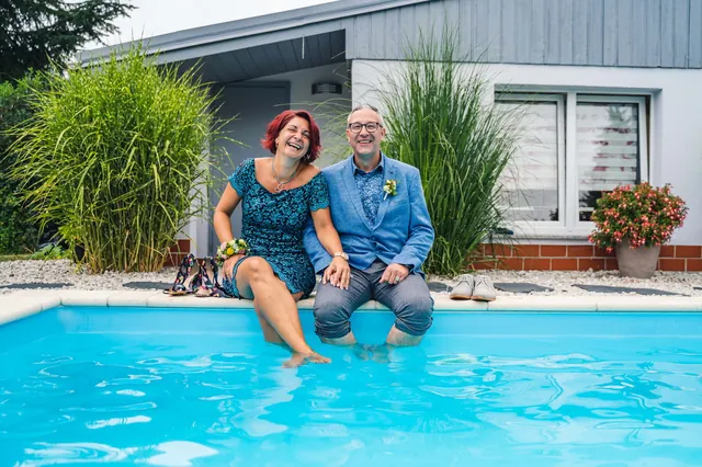 Zwei Hochzeitsgäste sitzen mit den Füßen im Pool